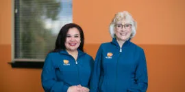 Winston Salem employees smiling in front of orange wall