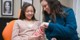 Orthodontic assistant wearing turquoise blue scrubs describing braces to teenage patient