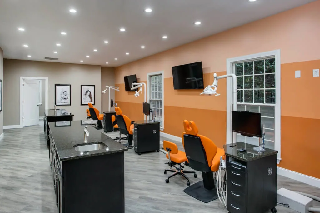 Southern Pines NC Orthodontic Bay with Orange striped fade wall and bright orange dental chairs