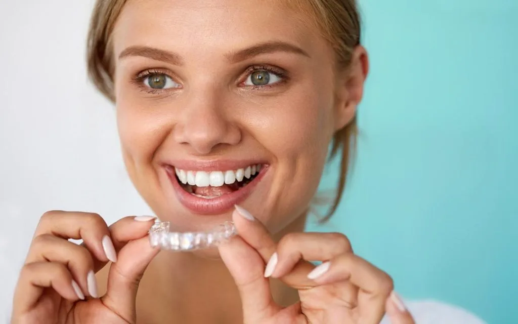 Invisalign cost vs Clear ceramic Braces cost girl holding invisalign aligners